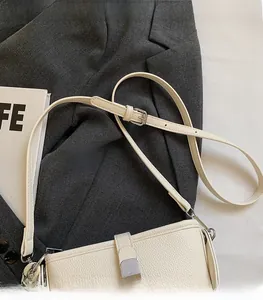 Détail de la texture cuir grainé blanc crème et boucle métallique argentée d'un sac à main