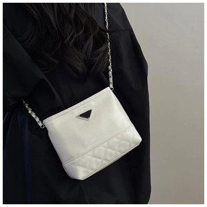 Detail of a cream bucket bag showing quilted leather stitching and a silver chain strap