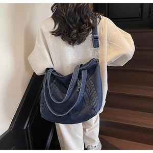 Detail of blue denim tote bag with adjustable shoulder strap shown on a model