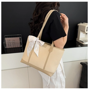Détail du sac cabas beige tissé avec foulard en soie rose et lanières en cuir