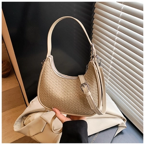 Detailed macro view of woven leather texture and silver buckle on the beige hobo bag