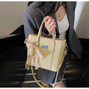 Dettaglio della borsa a secchiello intrecciata con elegante fiocco in pizzo e targhetta