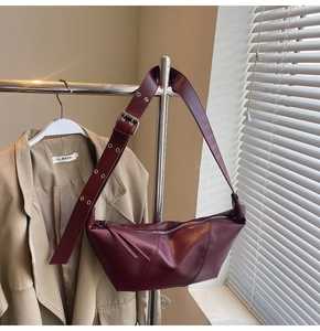 Detailed close-up of dark red leather half-moon bag with metallic eyelet strap details