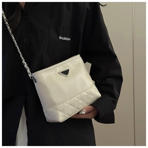 Detail of off-white quilted crossbody bag with metal triangle plaque and chain strap