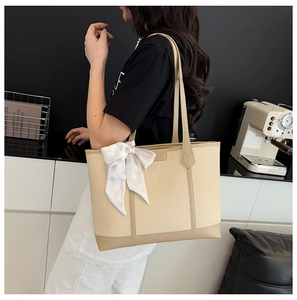 Détail du sac cabas tissé beige avec anses en cuir et foulard décoratif en soie à cœurs