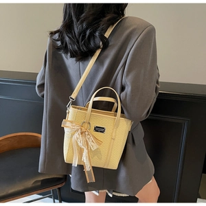 Dettaglio della borsa a secchiello beige con fiocco in pizzo e trama in PU trapuntata