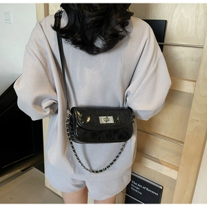 Close-up of black quilted leather crossbody bag with silver clasp on a model