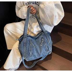 Close-up of vintage blue denim tote bag featuring diagonal zippers and washed texture