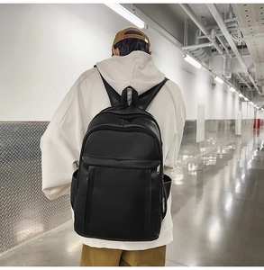 Urban lifestyle shot of a matte black leather backpack worn by a model in a corridor
