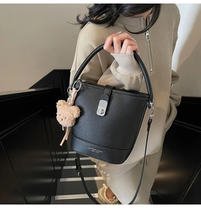 Détail du sac seau noir en cuir grainé avec fermoir argenté et breloque ours