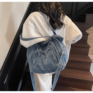 Detailed view of wash blue denim tote bag featuring zipper accents and wide shoulder strap