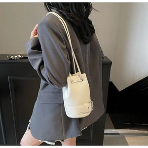 Détail du sac seau crème avec sangle à boucle argentée et fine bandoulière en cuir