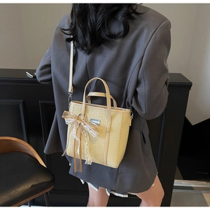 Dettaglio della borsa tote intrecciata crema con fiocco in pizzo e nastro di seta decorativo