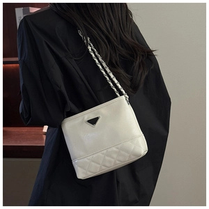 Detail view of large capacity quilted beige bucket bag with metal chain strap