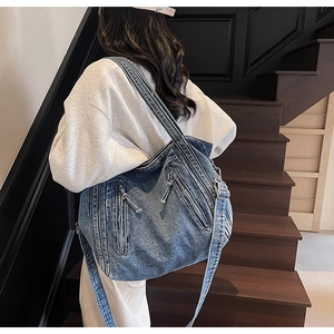 Detail of blue denim tote bag featuring multi-zipper pockets and washed retro texture