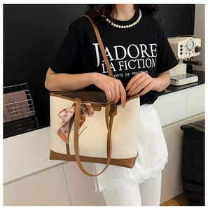 Détail du sac cabas tissé avec anses en cuir marron et foulard en soie décoratif
