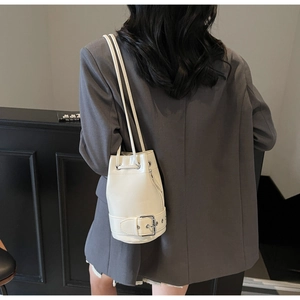 Vue portée du sac seau crème avec cordon de serrage et boucle métallique décorative