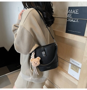 Détail du sac seau noir en cuir grainé avec fermoir argenté et charm ours en peluche