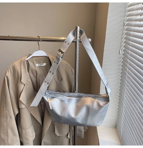 Detailed view of silver metallic crescent bag with eyelet strap on a hanger