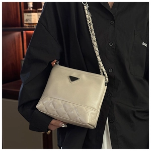 Detail of cream bucket bag featuring quilted pattern and metal triangle hardware