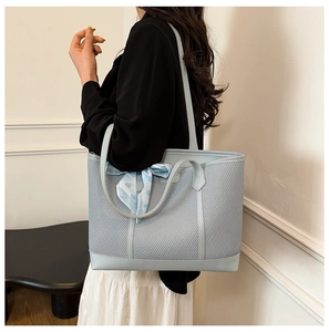Détail d'un sac cabas tissé bleu clair avec un foulard en soie décoratif à cœurs