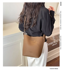 Brown lychee texture leather bucket bag with adjustable strap shown in a crossbody style