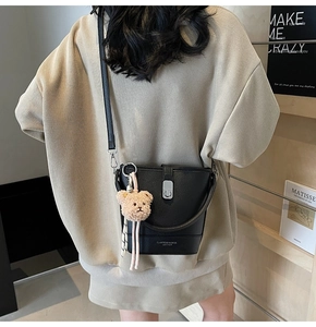 Détail du sac seau noir en cuir grainé avec fermoir rotatif et breloque petit ours