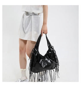 Detailweergave van zwarte hobo-tas met franjes, glanzende afwerking en lange kwastjes