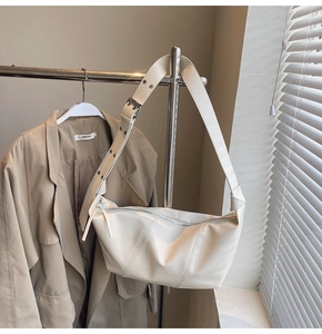Detail of cream shoulder bag featuring lychee texture leather and wide strap with silver buckle