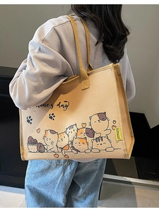 Khaki Leinwand-Einkaufstasche mit Cartoon-Katzenmotiven, von einem Model lässig getragen