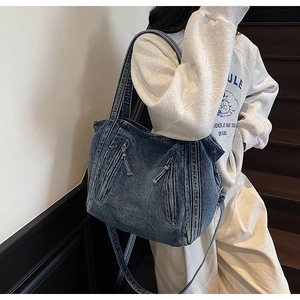 Detail of blue denim tote bag showing functional side pockets and adjustable strap design
