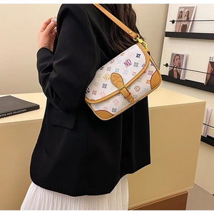 Side view of woman in black blazer carrying a white monogram patterned small square crossbody bag