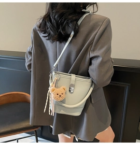 Détail du sac seau en cuir vert menthe avec un joli pendentif ours en peluche marron