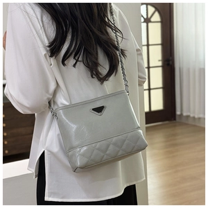 Detail of grey quilted bucket bag with silver chain strap and metal triangle plaque