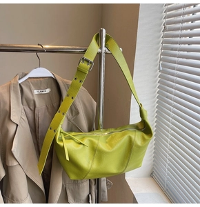 Lime green crescent shoulder bag with wide adjustable strap shown in a fashion setting