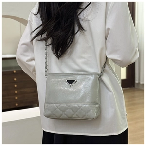Detail view of light grey quilted bucket bag with silver chain strap and metal triangle decor