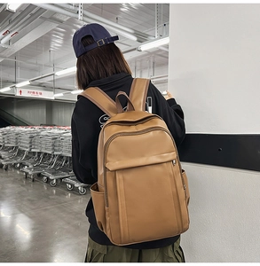 Detail view of the brown leather backpack back straps and spacious side pockets for travel