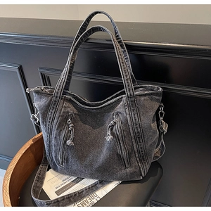 Detail of dark gray washed denim tote bag with dual zipper pockets and fringe tassels