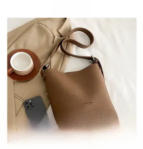 Detail of brown litchi pattern leather bucket bag with adjustable shoulder strap