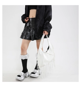 Detailopname van een witte laklederen shopper met lange franjes bij een model