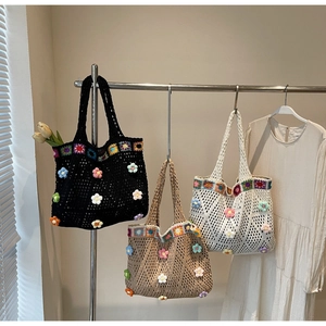 Dettaglio di tre borse tote fatte a mano all'uncinetto con fiori 3D colorati in luce soffusa