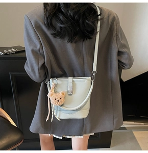 Détail d'un sac seau en cuir bleu clair avec pendentif ours et bandoulière chic