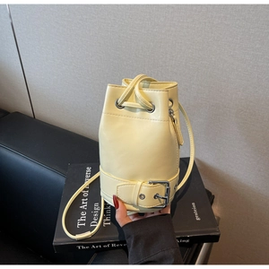 Détail du sac seau crème avec cordon de serrage, grain litchi et boucles métalliques