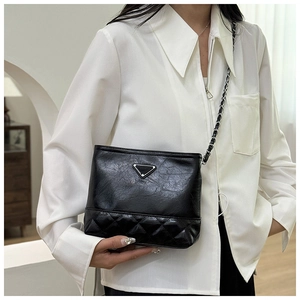 Detail of the chain strap and quilted faux leather texture on the black bucket bag