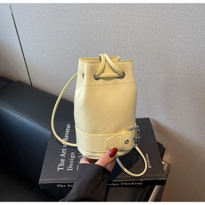 Détail d'un sac seau jaune avec fermeture à cordon et sangle décorative à boucle en métal