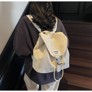 Close-up of cream canvas backpack featuring side zipper pocket and snap buckle detail