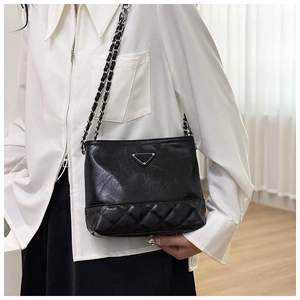 Detail of black leather chain shoulder bag featuring quilted pattern and metal logo