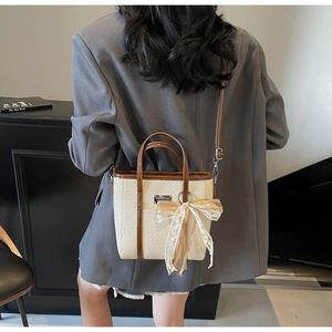 Detail view of cream crocodile texture bag with brown handles and lace bow accent
