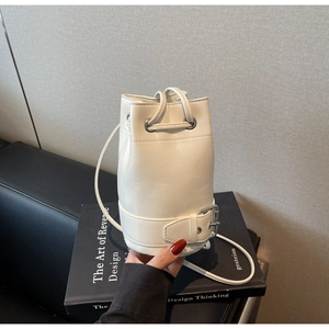 Détail du sac seau crème montrant la fermeture à cordon et les boucles argentées