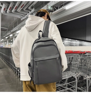 Detail of dark grey PU leather backpack showing sturdy texture and multiple pocket design